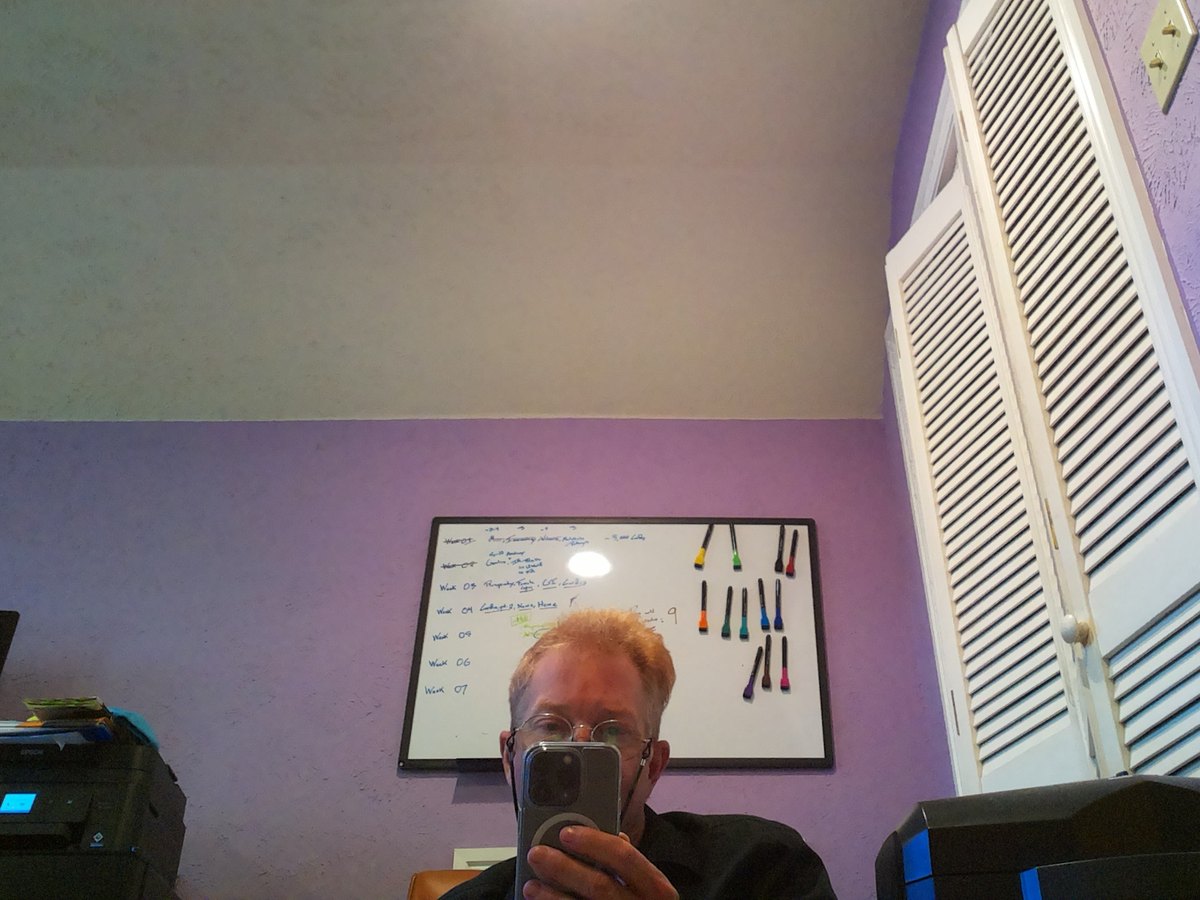 Stephen holding his phone, photographed from the floor by a small wheeled robot