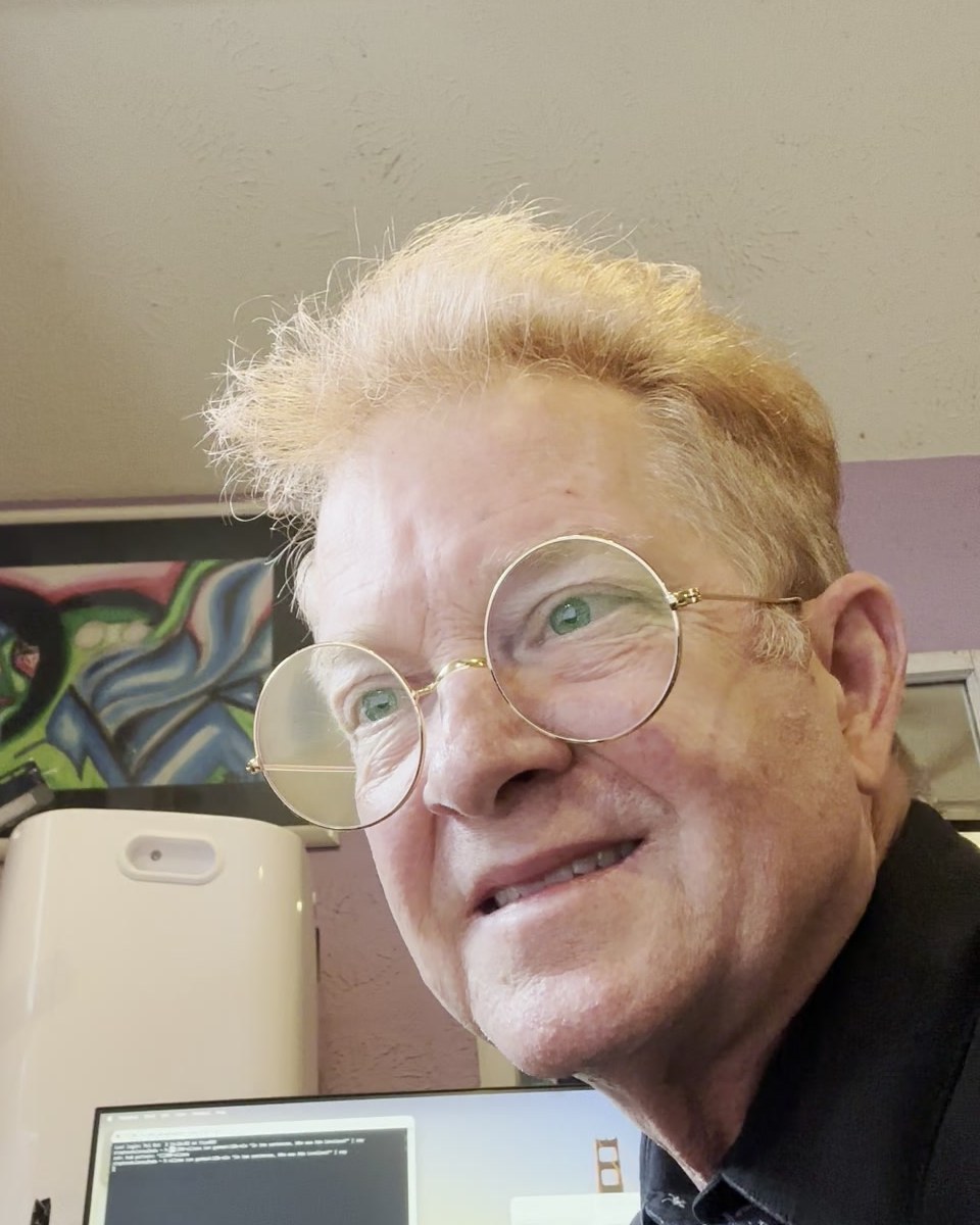 Stephen Dulaney smiling at his desk, with a new Mac mini behind him